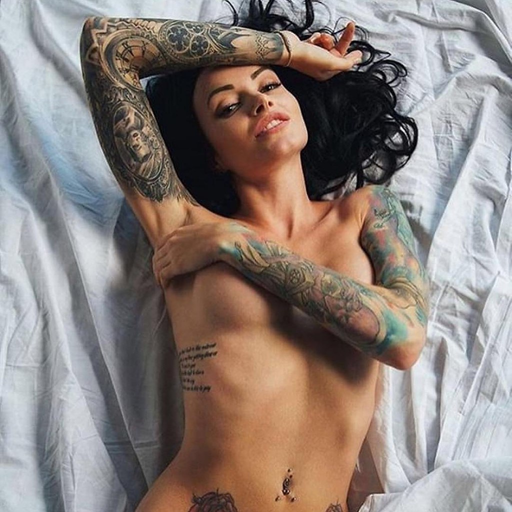 Татуированная брюнетка показывает голые сиськи и сексуальные ножки